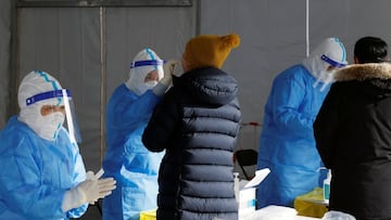 A medical worker in a protective suit collects a swab from a resident at a nucleic acid testing site outside a shopping mall, following the coronavirus disease (COVID-19) outbreak in Beijing, China January 26, 2022. REUTERS/Carlos Garcia Rawlins