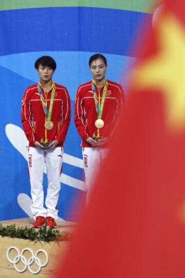 Gold medallists China's Wu Minxia (R) and Shi Tingmao listen to their national anthem during the podium ceremony of the Women's Synchronized 3m Springboard final event at the Rio 2016 Olympic Games at the Maria Lenk Aquatics Stadium in Rio de Janeiro on A