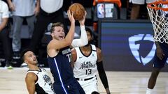 Luka Doncic, base de Dallas Mavericks lanza ante Landry Shamet y Paul George, de Los Angeles Clippers.