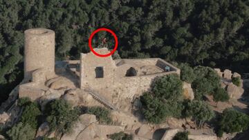 El piloto catalán de MTB Trial Pol Tarrés con su bici en lo alto del Castell de Burriac, en El Maresme (Barcelona, Cataluña, España) grabado por un dron y con el bosque de fondo.