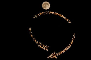 La luna se eleva tras un cartel antiguo en la cima de un edificio de apartamentos en el centro de la ciudad de Kansas City.