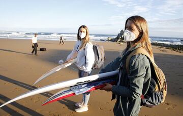 La surfista Leticia Canales, (d) top-10 del Mundo y tercera clasificada en el campeonato del mundo en Australia, junto a su hermana Loiola, (i) en la playa vizcaína de Sopelana donde ha entrenado tras 49 días de confinamiento. Desde este sábado, las personas mayores de 14 años pueden ir a pasear y hacer deporte individual, respetando unos horarios y la distancia de seguridad, unas salidas que se suman a los paseos de los niños que comenzaron a estar permitidos el pasado domingo tras semanas de confinamiento por el coronavirus. 