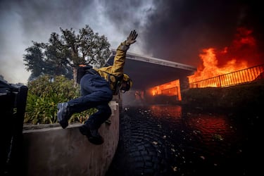 Un bombero salta una valla mientras lucha contra el incendio de Palisades en el barrio de Pacific Palisades de Los Ángeles.