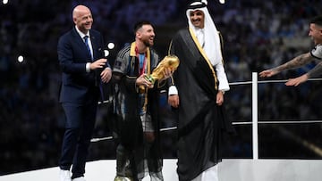 LUSAIL CITY, QATAR - DECEMBER 18: Lionel Messi of Argentina holds the FIFA World Cup Qatar 2022 Winner's Trophy as he interacts with Gianni Infantino, President of FIFA, and Sheikh Tamim bin Hamad Al Thani, Emir of Qatar