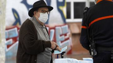 Transeúntes recogen mascarillas puestas a disposición de viajeros y usuarios de transporte público en las inmediaciones de la estación Intermoda, en Palma de Mallorca, Islas Baleares, (España), a 14 de abril de 2020.