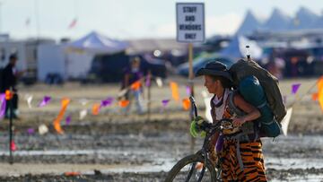 A Burning Man participant walks their bike through the mud near the exit, after a severe rainstorm left tens of thousands of revelers attending the annual festival stranded in mud in Black Rock City, in the Nevada desert September 3, 2023. Trevor Hughes/USA Today Network via REUTERS. MANDATORY CREDIT. NO RESALES. NO ARCHIVES