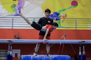 Un entrenador dirige una complicada y exigente sesión de preparación de un joven miembro del equipo nacional de gimnasta de Singapur. La imagen corresponde a la primera jornada de la Asamblea General de la Federación de Juegos de la Commonwealth, celebrada ayer en el Bishan Sports Hall de Singapur.