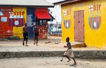 Unos niños juegan en el recinto del FC Barcelona en Fanti, Robertsport, una localidad del Condado de Grand Cape Mount (Liberia). El recinto del FC Barcelona es un pequeño barrio de pescadores, situado junto al lago Pisso, en el que Charles McCarthy y su familia, fanáticos del Barça, han pintado sus casas con los colores y el escudo blaugranas.