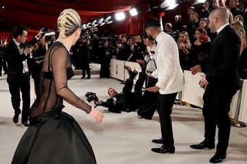 Lady Gaga reacciona mientras un fotógrafo cae sobre la alfombra roja durante las llegadas de los Oscar a los 95º Premios de la Academia en Hollywood.