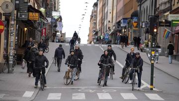 Varios ciclistas esperan a que el semáforo se ponga en verde para cruzar el paso de peatones.