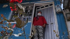 Mujer de escasos recursos parada en la puerta de su casa