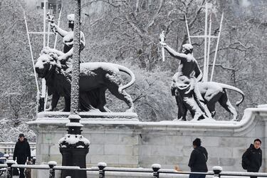 La gente camina al lado del monumento the Queen Victoria Memorial que se ve cubierto de nieve. 