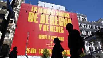 Viandantes pasan delante del cartel gigante colocado en la Gran Vía madrileña con un mensaje que está suscitando polémica en las redes: "En Madrid somos de derecha y de revés, vuelve la Copa Davis". La empresa