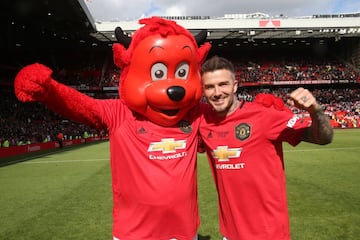 MANCHESTER, ENGLAND - MAY 26:   David Beckham of Manchester United '99 Legends celebrates with Fred the Red at the end of the 20 Years Treble Reunion match between Manchester United '99 Legends and FC Bayern Legends at Old Trafford on May 26, 2019 in Manc