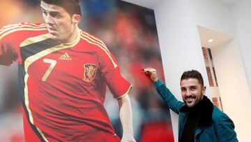 David Villa, posa junto a una imagen suya con la Selección en Gijón.