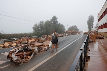 Un hombre pasa junto a objetos dañados de una fábrica de muebles afectada por las lluvias torrenciales que provocaron inundaciones en La Alcudia, región de Valencia.