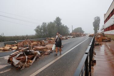 Un hombre pasa junto a objetos dañados de una fábrica de muebles afectada por las lluvias torrenciales que provocaron inundaciones en La Alcudia, región de Valencia.