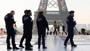 Officers of the French National Police patrol in front of the Eiffel Tower after the installation of the Olympic rings on the tower for the upcoming Paris 2024 Olympic Games, in Paris on June 7, 2024. (Photo by JOEL SAGET / AFP)