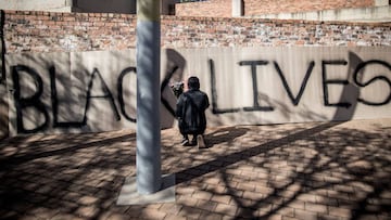 An activist kneels near a banner with the slogan &#039;Black Lives Matter&#039; at the Constitutional Hill precinct in Johannesburg, on June 14, 2020 during a Black Lives Matter vigil. - A wave of global protests have taken place in response to anti-racis