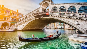Beautiful view of traditional Gondola on famous Canal Grande with Rialto Bridge at sunset in Venice, Italy with retro vintage Instagram style filter and lens flare effect.