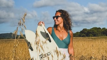 Giulia Manfrini con una tabla de surf twin fin en un campo de trigo.