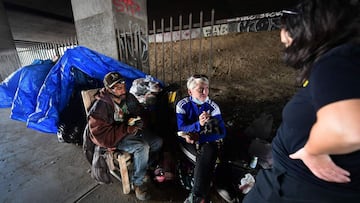 Dos sintecho hablan con una activista tras el desalojo de un campamento de personas sin hogar por parte de las autoridades de Los &Aacute;ngeles cerca del SoFi Stadium, sede de la Super Bowl LVI.