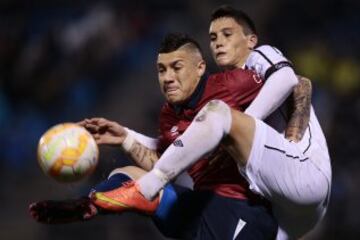 Christian Bravo disputa el balón con Federico Ricca del Danubio de Uruguay.