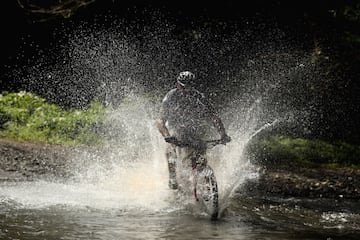 El ciclista de Costa Rica Roger Abarca Jiménez cruza un río en la localidad de Jacó. 