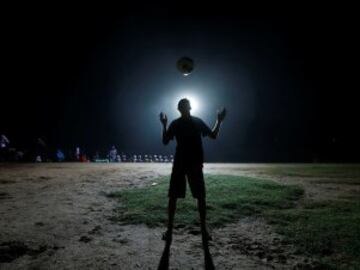 Silueta de un niño jugando con un balón de fútbol en la noche en Colombo 