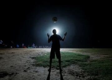 Silueta de un niño jugando con un balón de fútbol en la noche en Colombo 