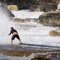 Una ola gigante estampa a un fotógrafo de surf contra las rocas
