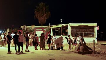 Varios j&oacute;venes conversan en la playa de la Barceloneta, en Barcelona, anoche, tras el cierre de discotecas decretado por las autoridades catalanas.