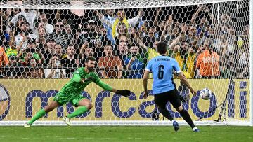 Uruguay's midfielder #06 Rodrigo Bentancur scores as Brazil's goalkeeper #01 Alisson dives for the ball in a penalty shoot-out during the Conmebol 2024 Copa America tournament quarter-final football match between Uruguay and Brazil at Allegiant Stadium in Las Vegas, Nevada on July 6, 2024. (Photo by Frederic J. Brown / AFP)