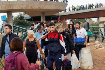 Personas transportan suministros para ayudar a las zonas afectadas por las inundaciones caminan por un camino fangoso, tras las lluvias torrenciales que provocaron inundaciones, en Valencia.