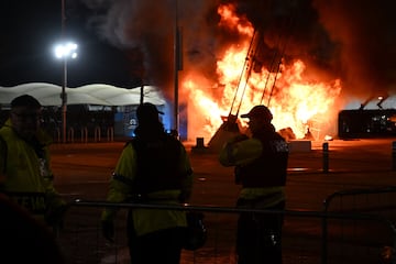 La policía observa mientras las llamas envuelven un puesto de venta de productos en llamas en el exterior del estadio Etihad en Mánchester.