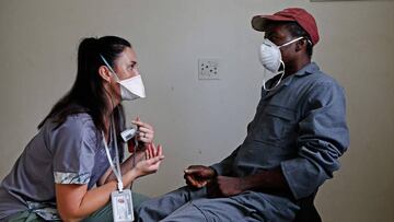 Dr. Stonehouse (L) consults a homeless man who complained of chest pains after administering Methadone Oral Solution, provided as an effort to care for drug dependent people, at a shelter at the Lyttelton Sports Centre in Pretoria on April 16, 2020 where temporarily shelter are being provided for homeless people amid the COVID-19 coronavirus situation in South Africa. (Photo by Phill Magakoe / AFP)