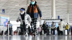 People wearing face masks walk through a departure lobby of Beijing Capital International Airport on Dec. 27, 2022. China said the previous day it will reopen borders and abandon quarantine measures that have been in place to stem the spread of coronavirus infections on Jan. 8, in a shift away from its strict "zero-COVID" policy. (Photo by Kyodo News via Getty Images)