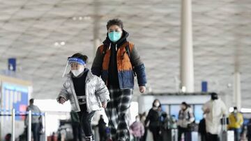 People wearing face masks walk through a departure lobby of Beijing Capital International Airport on Dec. 27, 2022. China said the previous day it will reopen borders and abandon quarantine measures that have been in place to stem the spread of coronavirus infections on Jan. 8, in a shift away from its strict "zero-COVID" policy. (Photo by Kyodo News via Getty Images)