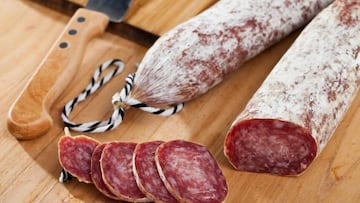 Spanish longaniza sausages cut in slices on a wooden surface, close-up