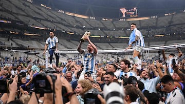 Argentina's forward #10 Lionel Messi (C) lifts the FIFA World Cup Trophy as he celebrates with Argentina's forward #22 Lautaro Martinez (R) and supporters winning the Qatar 2022 World Cup final football match between Argentina and France at Lusail Stadium in Lusail, north of Doha on December 18, 2022. (Photo by Kirill KUDRYAVTSEV / AFP)