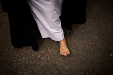 Una penitente de la hermandad de Santa Genoveva camina descalza en señal de penitencia mientras procesiona por las calles de Sevilla en Lunes Santo.