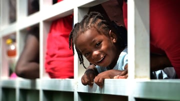 A migrant girl heading in a caravan to the border with Guatemala, smiles onboard a truck in Cerro Hula, 10 km south of Tegucigalpa, on June 3, 2020. - Almost a hundred migrants from Congo, Ghana, Ivory Coast, Haiti and Cuba heading in a caravan from Cholu