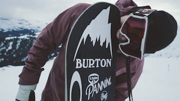 La snowboarder de Barcelona Maria Hidalgo mordiendo su tabla de snowboard con las pegatinas de Oakley, Burton, Pannini y Buff en Laax (Suiza) este invierno, con nieve al fondo, durante la grabaci&oacute;n de su proyecto Inside Me.