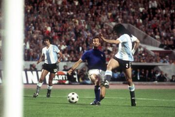 Primer enfrentamiento en partido oficial entre Argentina y Alemania, y sería nada más y nada menos que en una fase final de mundial. Alemania Occidental era la anfitriona del torneo, y ambos combinados se veían las caras en el grupo 4, donde también estaban Polonia y Haití. El encuentro se celebró en la segunda jornada, y acabó siendo decisivo en las aspiraciones de ambos conjuntos. Ambas selecciones vencieron cómodamente a Haití, y cayeron ante una Polonia que hizo pleno de
victorias. El Argentina vs Italia concluyó con empate a 1, lo que concluyó en empate a puntos, y por tanto hubo que recurrir a la diferencia de goles que fue mínima, para decidir al equipo clasificado, que fue Argentina. El choque estuvo muy igualado, Houseman adelantaría en el minuto 19 a Argentina, y
Perfumo con un gol en propia pondría las tablas definitivas del primer encuentro de las dos históricas en el torneo más importante a nivel de selecciones. En la foto del partido, Rubén Hugo Ayala ante el defensa italiano Luciano Spinosi bajo la mirada de Mario Kempes, 