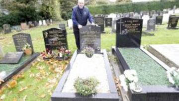UNA LÁPIDA CON UN BALÓN DE FÚTBOL. Graham, el hijo mediano de Bob y Jessie Paisley, posa junto a la tumba de sus padres.
