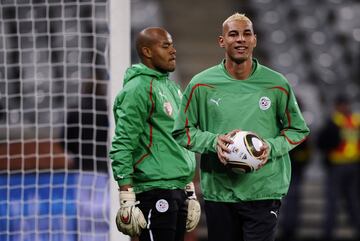 Al igual que Robert Green, Faouzi Chaouchi, portero argelino (en la imagen con el balón en la mano), sufrió también feroces críticas de la prensa de su país. Había sido uno de los héroes en el partido que enfrentó a Argelia y a Egipto en Sudán y que permitió a 'los zorros de desierto' acudir a Sudáfrica. Pero ese error le costaría su puesto en la selección nacional. Le sustituiría M'Bohli, el portero que aparece a su lado...