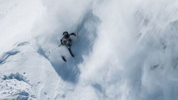 Un esquiador levantando nieve en una monta&ntilde;a. 