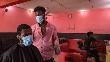 Kofi (C), a barber, resumes work after the partial lockdown in parts of Ghana to halt the spread of the COVID-19 coronavirus was lifted in Accra, Ghana on April 20, 2020. - The streets of Accra buzzed with life following President Nana Akufo-Addo's a