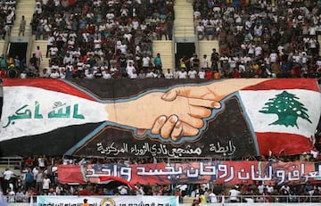 Football fans hold a large banner bearing the colours of the Lebanese (R) and Iraqi flag during the AFC Cup football match between Al-Zawraa and Al-Ahed at the Karbala Sports City stadium on April 10, 2018.