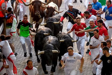 El séptimo encierro de las fiestas de San Fermín discurrió  sin incidentes reseñables. En la imagen se ve a algunos aficionados al fútbol, con camisetas del Real Madrid y de Osasuna, corriendo delante de los toros. A buen seguro que en su carrera añoraban la tranquilidad de ver el fútbol desde la grada, sin riesgos.